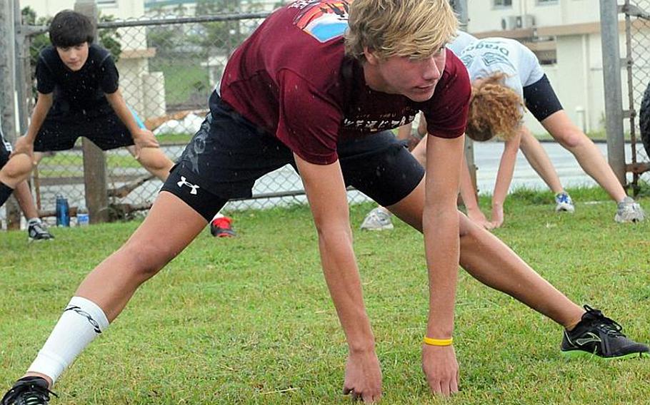 Kubasaki Dragons sophomore and reigning island and Far East cross-country champion Erik Armes limbers up before a practice at Camp Foster, Okinawa. Visible on Armes&#39; right leg is a compression sleeve to help him continue rehabilitating from a stress fracture suffered last spring.