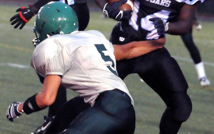 Osan American ball carrier T.J. Busano eludes the tackle of Daegu defender Caleb Page during Friday's DODDS Pacific Far East Division II and DODDS Korea regular-season game at Camp Walker, South Korea. The Warriors downed the Cougars 26-15.