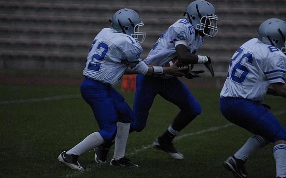 Brussels sophomore quarterback Hayden Pfefferkorn hands the ball off to senior Kristian Javier during Friday night's game at Baumholder. Brussels fell to host Baumholder, 57-6.