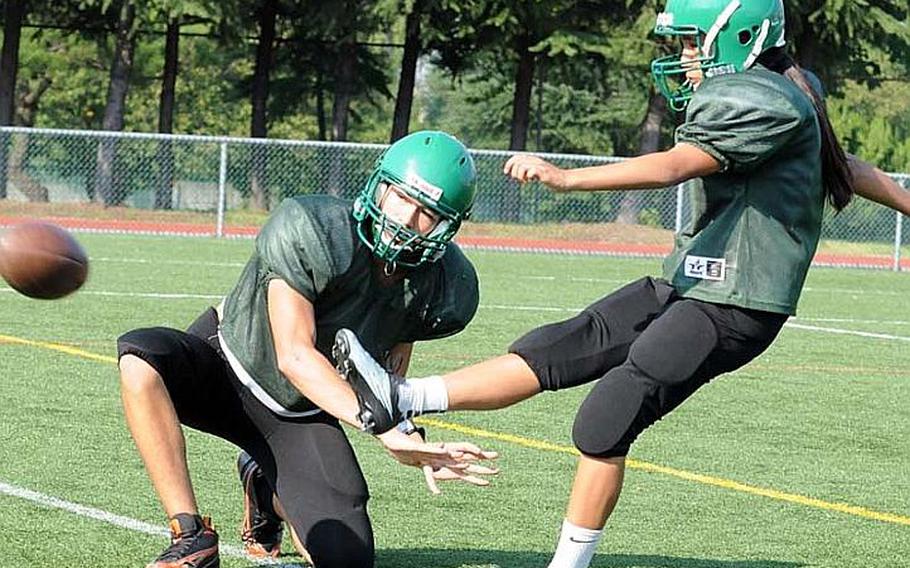 Daegu junior Monica Morales, the third girl in Warriors history to placekick, boots a PAT try out of the hold of Caleb Page during Monday's practice at Camp Walker, South Korea.