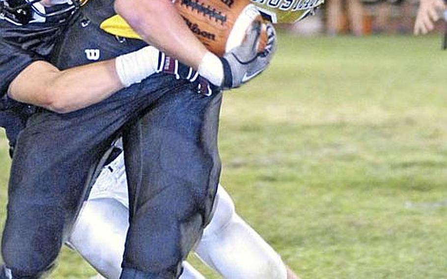 American School In Japan receiver Henry Wallrapp is brought down by Zama American defender Osie Cruz during Friday's Kanto Plain Association of Secondary Schools football game at Camp Zama, Japan. ASIJ won 24-8.