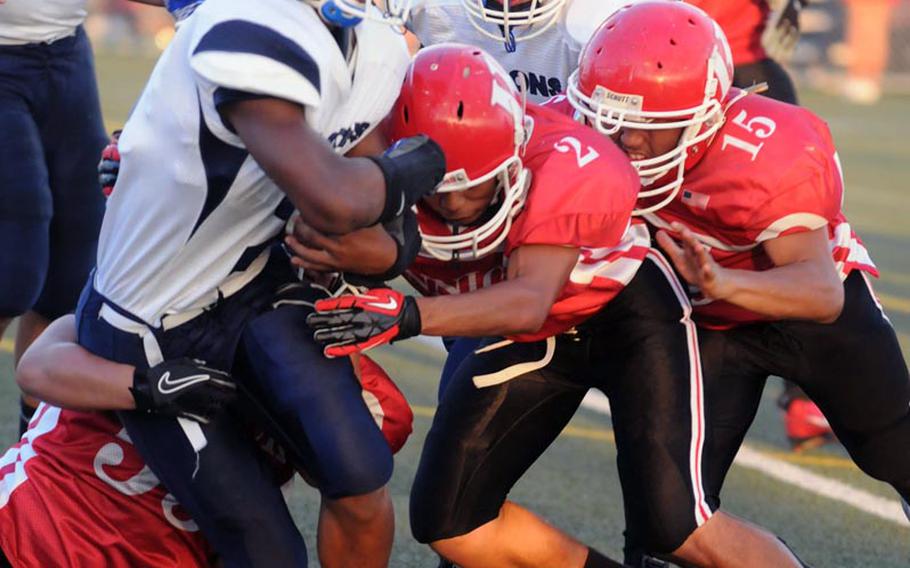 Seoul American running back Ronald Dogan gets tackled by Nile C. Kinnick defenders Marvin Newbins, Alex Banks and Jesse Ecklund during Saturday's Far East Division I football game at Yokosuka Naval Base, Japan. Kinnick beat the Falcons 27-0 to stay alive for a berth in the D-I title game on Nov. 17.