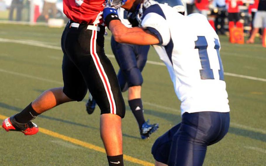 Nile C. Kinnick defender Marvin Newbins gets hit by Seoul American defender Louis Swafford as he catches the ball during Saturday's Far East Division I football game at Yokosuka Naval Base, Japan. Swafford knocked the ball out of Newbins' hands for an incompletion. 