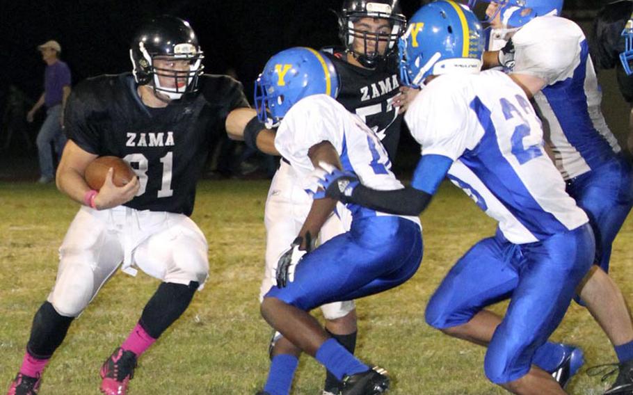 Zama American running back Andre Encarnacion gets an escort from teammate Josh Elliot as Yokota  defenders J.J. Henderson and Morgan Breazell close in during Friday's DODDS Japan/Kanto Plain Association of Secondary Schools football game at Camp Zama, Japan. Yokota won 39-12 and clinched its 12th DODDS Japan and Kanto titles on coach Tim Pujol's watch.