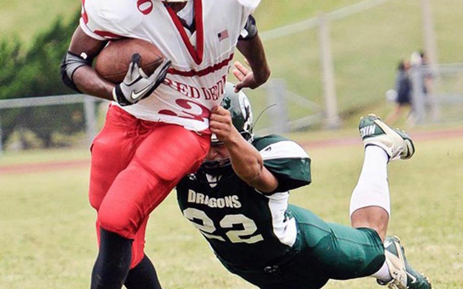 Kubasaki's Sho Green gets a fistful of Nile C. Kinnick  running back LaTendre Paylor's jersey during Saturday's DODDS Pacific Far East Division I regular-season game at Camp Foster, Okinawa. The Dragons won 28-14, keeping charge of the race for D-I title-game berths, while eliminating the Red Devils from title contention.