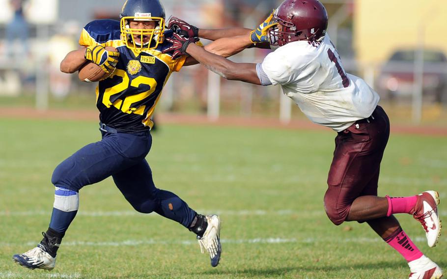 Heidelberg's Justin Rodney, left, tries to keep Vilseck's Carlton Campbell at arm's length in Division I action in Heidelberg, Saturday. Heidelberg fell to the Falcons 34-26 in the Lions' final football game.