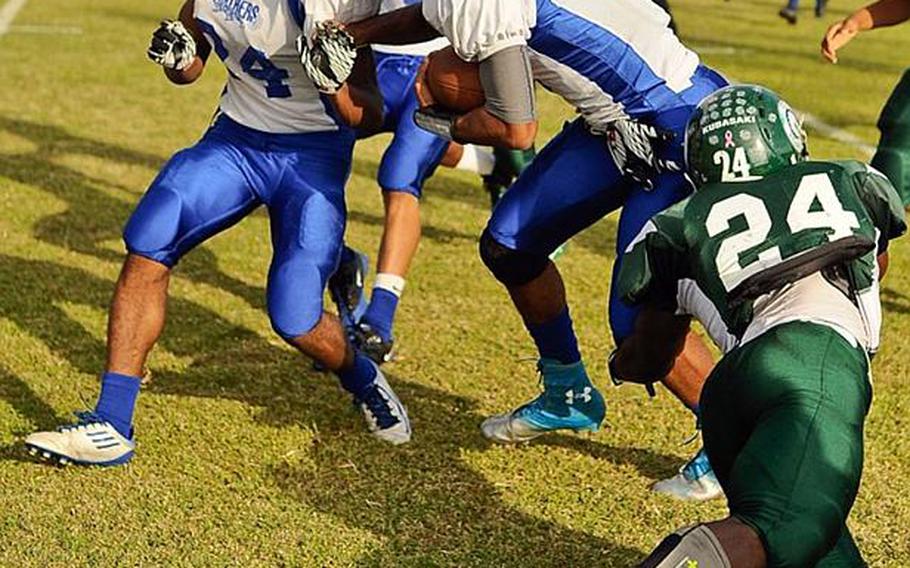 Yokota quarterback Stanley Speed gets an escort from teammate Raymond Butler as Kubasaki  defender Jarrett Mitchell tries to make the tackle during Saturday's DODDS Pacific Far East Division I football game at Camp Foster, Okinawa. Yokota won 31-6.