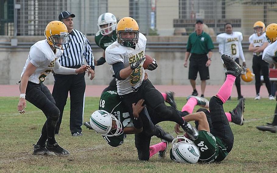 SHAPE's Conner Manning gets brought down by Naples' Tyler Williams, right, and Nicholas Snider.