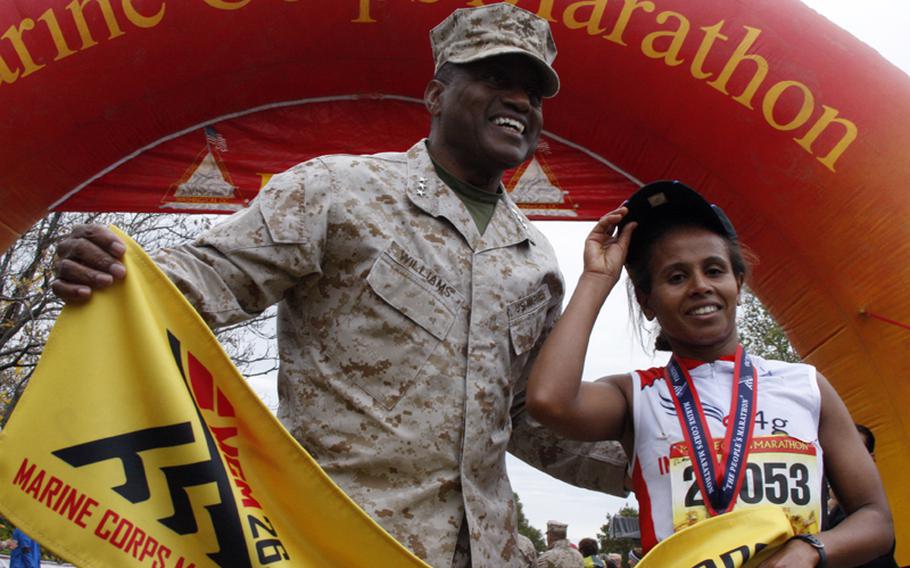 Lt. Gen. Willie Williams presents Hirut Guangul with the finish line tape at the 2012 Marine Corps Marathon awards ceremony on Sunday, Oct. 28. Guangul was the first woman to cross the finish line with a time of 2:42:03.