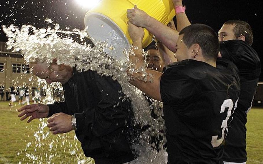 Zama American coach Steven Merrell gets the water-bucket treatment from seniors Andre Encarnacion and Michael Torres late during Saturday's DODDS Pacific Far East High School Division II football championship game at Camp Zama, Japan. Zama beat Robert D. Edgren 35-20 for its second D-II title in four years.