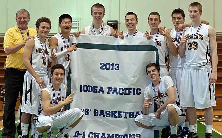 American School In Japan coach Brian Kelley and his players celebrate with the banner after Thursday's championship game in the Far East High School Boys Division I Basketball Tournament at Camp Foster, Okinawa. The Mustangs won their first D-I title since 1983, beating Father Duenas Memorial 61-49.