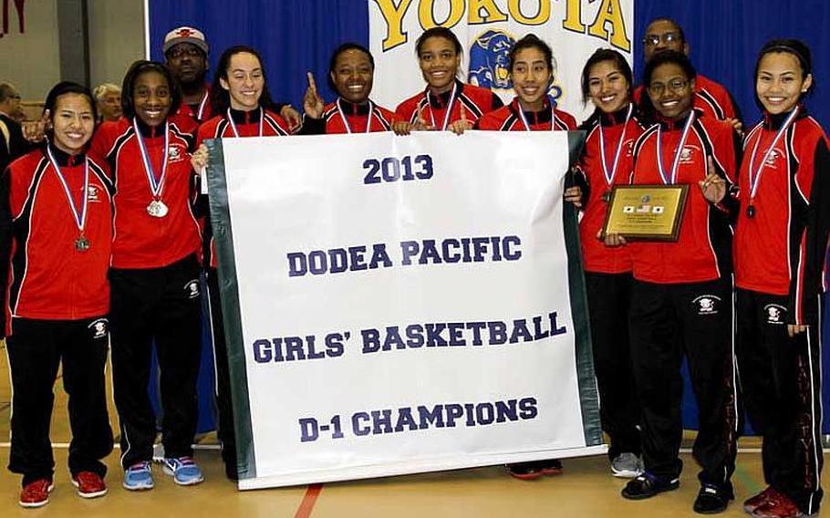 Nile C. Kinnick's players celebrate with the banner after Thursday's championship round of the Far East High School Girls Division I Basketball Tournament at Yokota Air Base, Japan. The Red Devils won their first title in 12 years, beating American School In Japan 45-32 in the second of two championshiip games. The Mustangs forced the second game by edging Kinnick 57-53 in overtime.