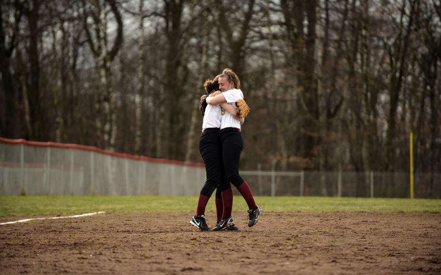 Baumholder High School softball team's shortstop Paige Williams, right, hugs third baseman Liz Jacobson after making a play to throw out a Ramstein base runner in a recent game at Baumholder, Germany.