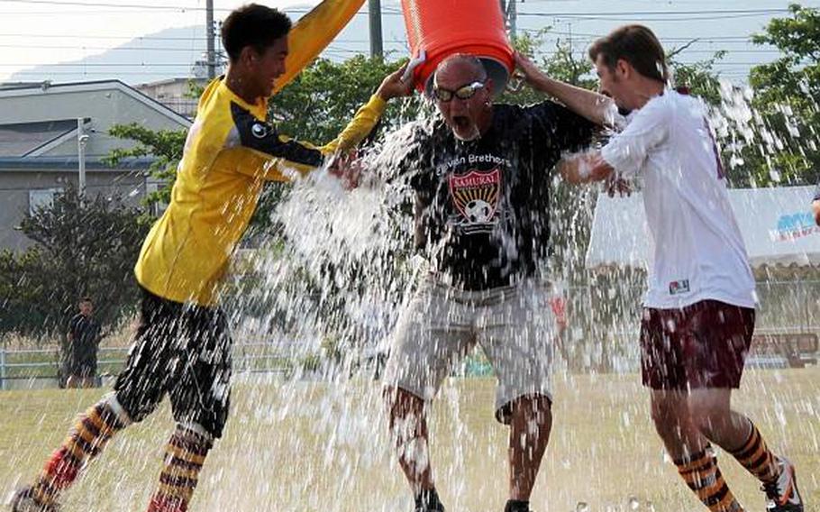 Matthew C. Perry's boys soccer coach Mark Lange gets the water-bucket treatment from Sam Cadavos and Robert Whiteside after Thursday's championship match in the Far East High School Boys Division II Soccer Tournament at Marine Corps Air Station Iwakuni, Japan. The Samurai repeated their championship, beating Osan American 3-1.