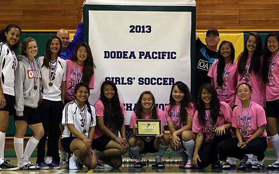 Osan American players and coaches pose with the title banner after Thursday's championship match in the Far East High School Girls Division II Soccer Tournament at Misawa Air Base, Japan. The Cougars dethroned Matthew C. Perry, shutting out the Samurai 4-0 behind four Ebony Madrid goals.