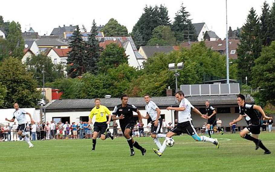The city of Baumholder looms in the background as players from Ohio Wesleyan University and the German Forces national team play a friendly match Wednesday at Bruehlstadion in Baumholder, Germany. The German Forces national team beat OWU 2-1. OWU visits Baumholder every three to five years as part of a two-week visit to Germany.
