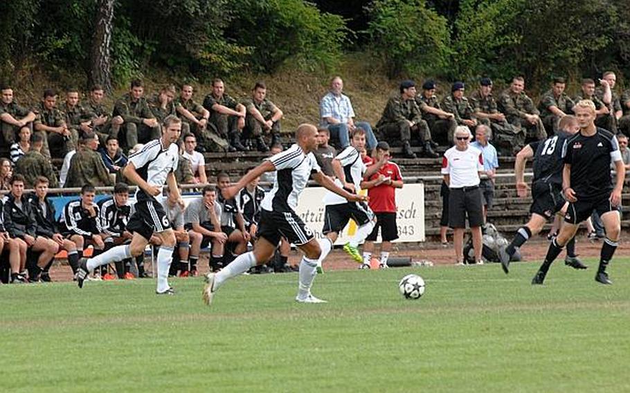 German Forces soldiers line the stands behind the Ohio Wesleyan University bench to watch the German Forces national team face OWU in a friendly match Wednesday at Bruehlstadion in Baumholder, Germany. The German Forces national team beat OWU 2-1. OWU visits Baumholder every three to five years as part of a two-week visit to Germany.