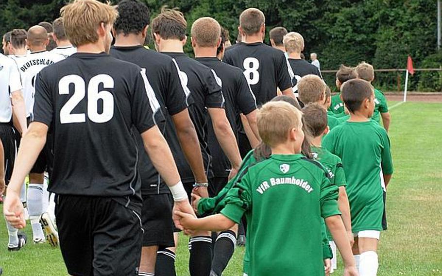 Members of the Ohio Wesleyan University soccer team are escorted onto the field by players from the VfR Baumholder youth team Wednesday at Bruehlstadion in Baumholder, Germany. The German Forces national team beat OWU 2-1. OWU visits Baumholder every three to five years as part of a two-week visit to Germany.