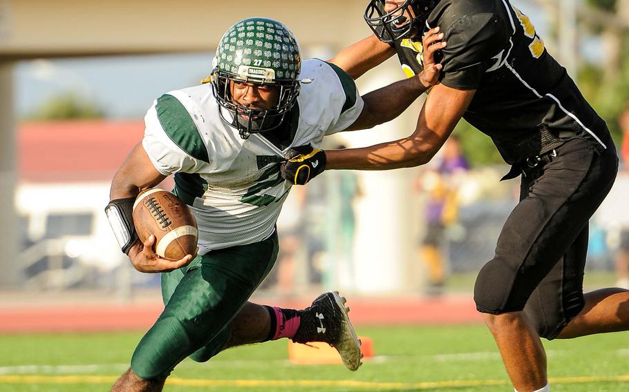 Kubasaki running back Tyshon Butler stiff-arms Kadena defender Damien Pierre, who grabs a fistful of Butler's jersey during Saturday's DODDS Pacific Far East High School Division I football championship game at Kadena Air Base, Okinawa. Kubasaki beat Kadena 34-31 in overtime.