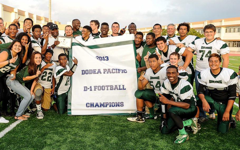 Kubasaki players, coaches and managers crowd around the championship banner after Saturday's DODDS Pacific Far East High School Division I football championship game at Kadena Air Base, Okinawa. Kubasaki edged the Kadena Panthers 34-31 in overtime.