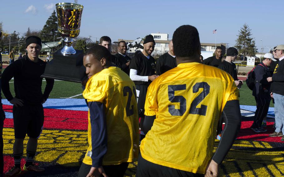 Navy players celebrate with the trophy following the annual Army-Navy flag football game Saturday at  Naval Air Facility Atsugi, Japan. Navy led 13-0 at half and hung on to win 13-12.