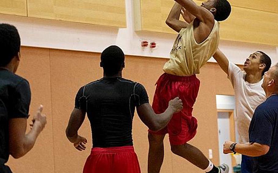 Jamar Walker goes up for a layup while his teammates and coach look on during a practice. 