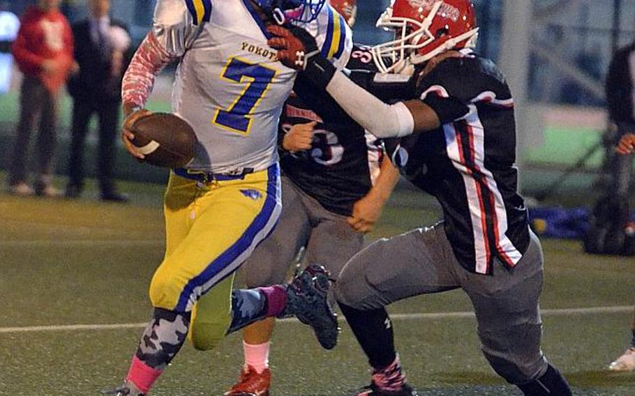 Yokota senior QB Marcus Henagan tries to elude the tackle of Nile C. Kinnick defender Darius Swenson.