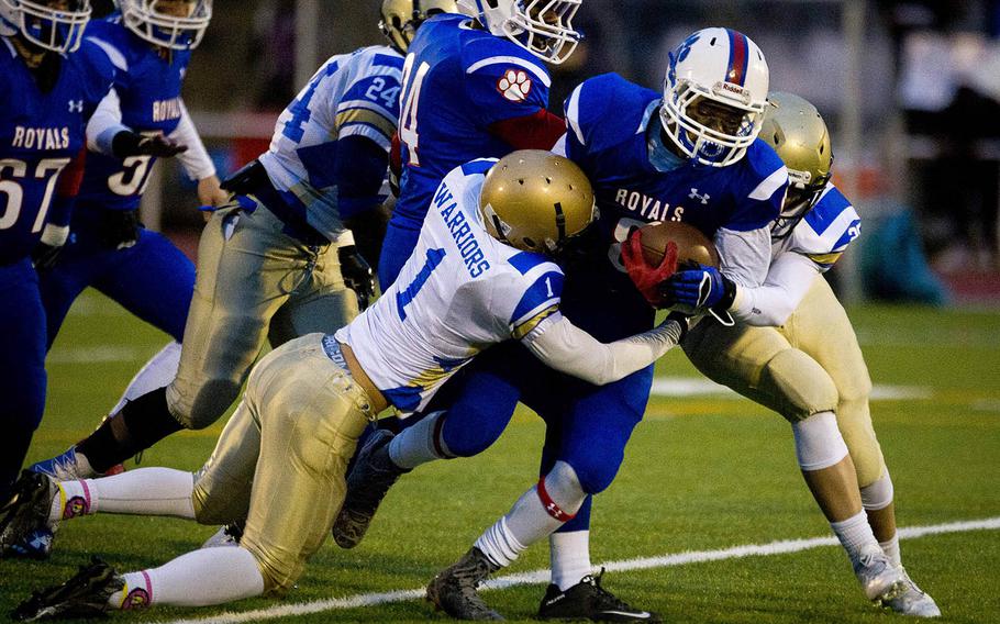Ramstein's Ryan Morgan is brought down by Wiesbaden's Chance Arnoldussen, left, and Allen Quitagua during the DODEA-Europe Division I championship at Vogelweh, Germany, on Saturday, Nov. 5, 2016. Ramstein won 13-6.