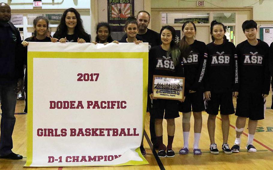 American School of Bangkok players and coaches gather round the banner following their 52-31 win Thursday over Kadena in the Far East Girls Division I Tournament final.