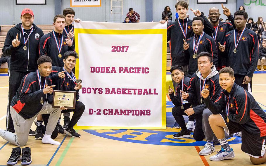 E.J. King players and coaches gather round the banner following their 67-66 win Thursday over host and two-time defending champion Yokota in the Far East Boys Division II Tournament final.