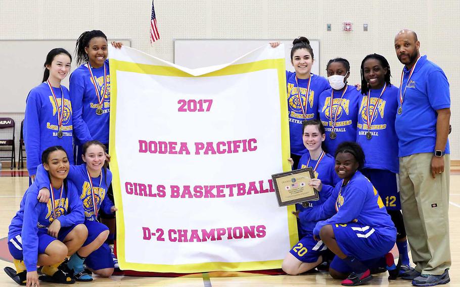 Yokota players and coaches gather round the banner following their 42-35 win Thursday over Robert D. Edgren to win their third straight Far East Girls Division II Tournament title.