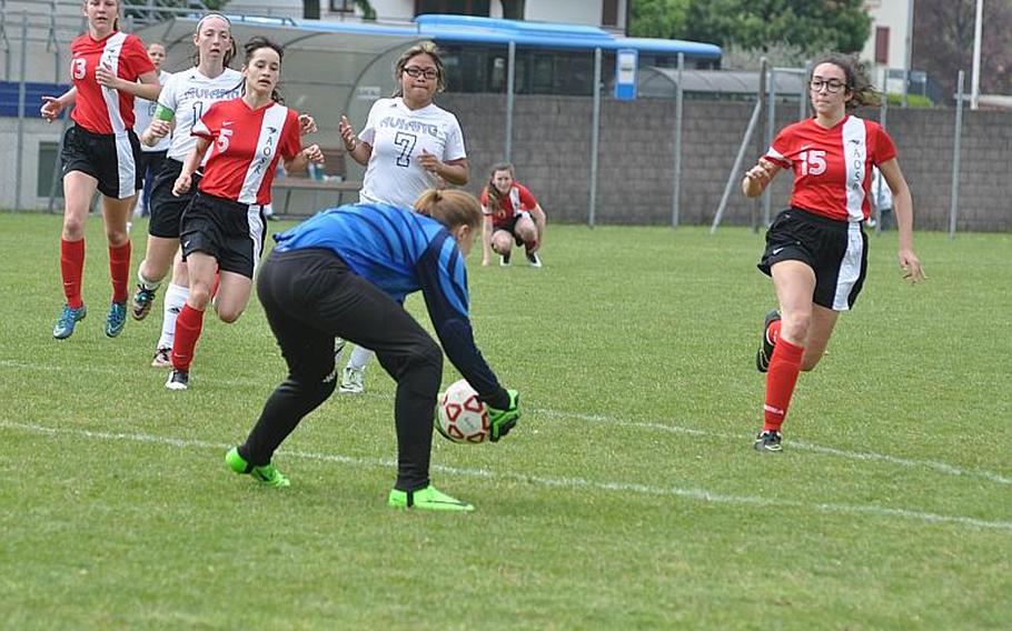 Aviano goalkeeper Saskia Zaremba scoops the ball up right before a horde of players gets to her spot in the Saints 4-3 victory Saturday over American Overseas School of Rome.