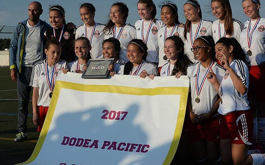 Nile C. Kinnick players and coach Nico Hindie gather round the banner after Thursday's Far East Girls Division I Soccer Tournament final, won by the host Red Devils 3-0 over American School In Japan.

DAVE ORNAUER/STARS AND STRIPES
