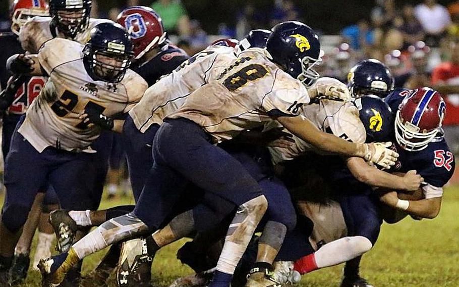 Okkodo ball carrier Ethan Sanchez gets dogpiled by a pack of Guam Panthers during Friday's football game, won by the Panthers 30-0.