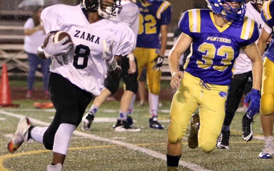 Zama American's Jay Webb takes a handoff around right end against Yokota's Logan Ferch during Friday's football game. The Panthers routed the Trojans 56-20.