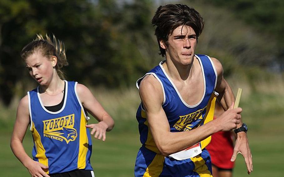 Siblings Jarod and Emily Swain pass the baton during Thursday's team relay phase of the Far East cross country meet. Swain and Swain finished first and Yokota swept all three team titles to win the overall school banner for the second straight year.