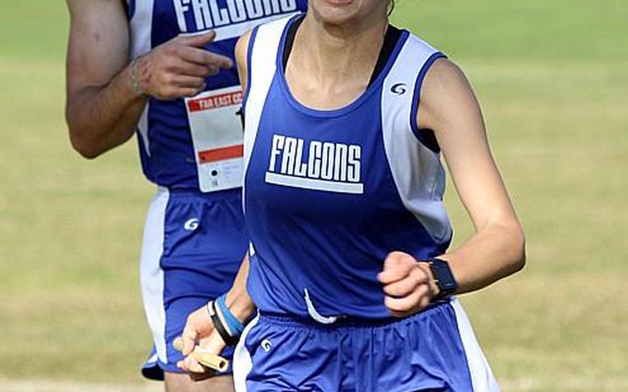 Tucker Chase shouts encouragement after passing the baton to teammate Chloe Byrd during Thursday's team-relay phase of the Far East cross country meet. The two crossed the finish line first and Seoul American won the boys team title.