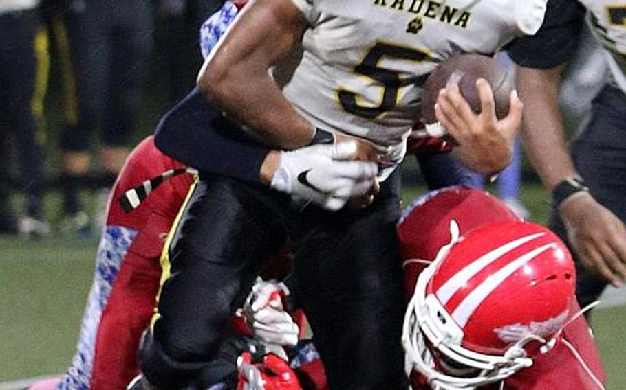 Kadena running back Eric McCarter slithers through the tackle of a pair of Red Devils defenders.