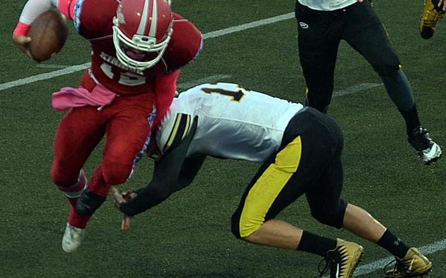 Nile C. Kinnick quarterback Kacey Walker tries to evade the tackle of Kadena's Owen Sinning.