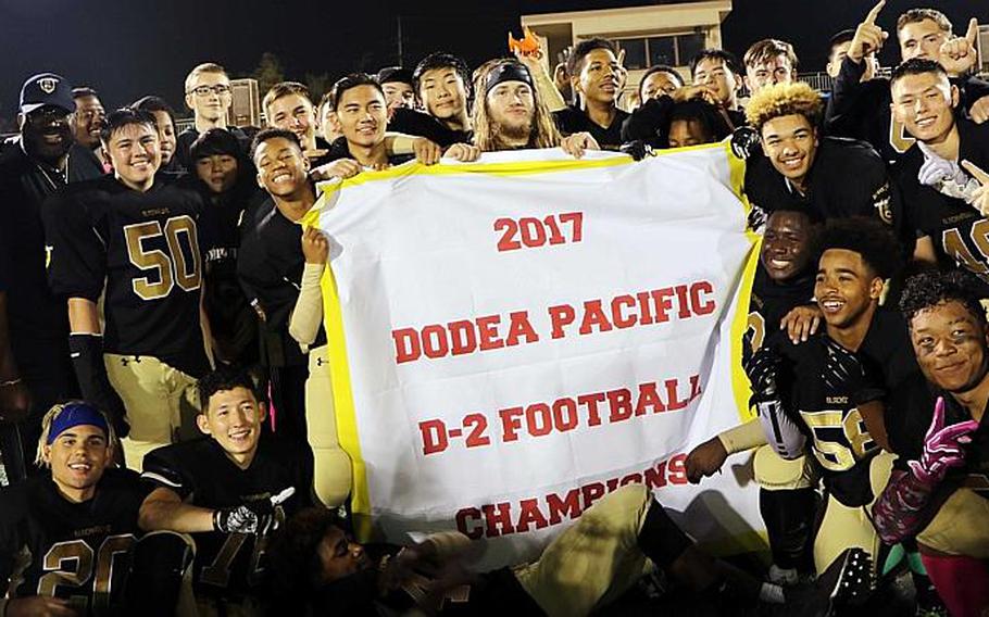 The champion Humphreys Blackhawks gather around the Far East Division II football banner.