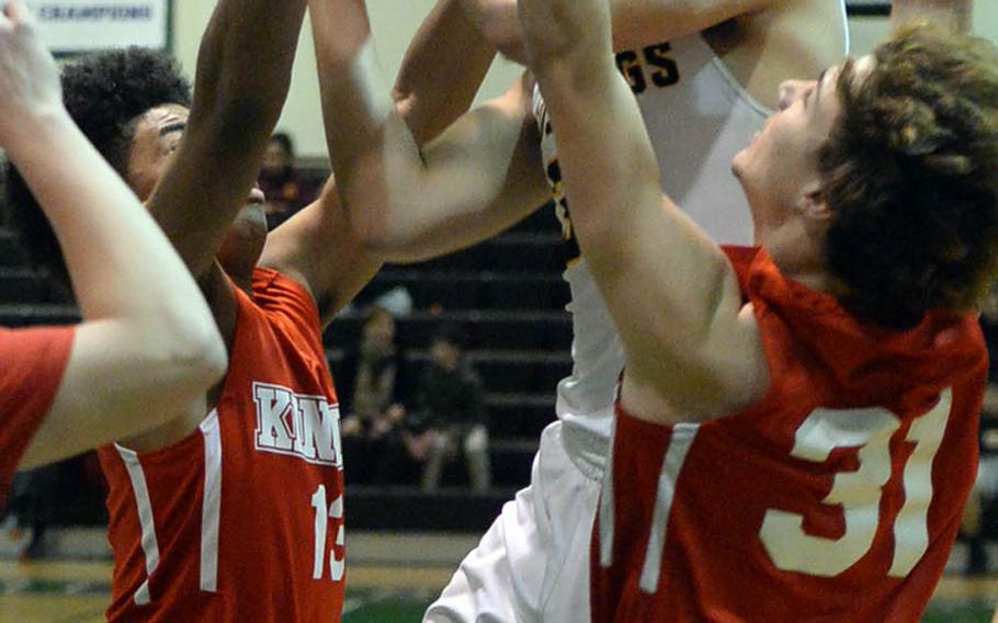American School In Japan's Koki Wiley grimaces as he tries to shoot between Nile C. Kinnick's Kedrick Stockman and Aaron Peterson during Tuesday's final in the Far East Boys Division I Basketball Tournament. The Red Devils routed the Mustangs 75-50 for the first tournament title in Kinnick school history.