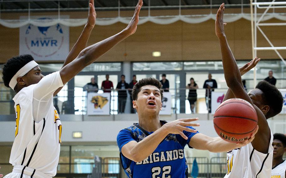 Brussels' Shahzod Niyazov goes for a layup between Baumholder's Chandler Pigge', left, and Kwameer Gindraw during the DODEA-Europe Division III championship in Wiesbaden, Germany, on Saturday, Feb. 24, 2018.
