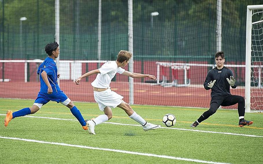 Brussels' Ben Gray takes a shot on Ansbach's Nick Benson, right, as Rommel Sebastian Penaflor drops back to assist during the DODEA-Europe Division III soccer championship in Kaiserslautern, Germany, on Thursday, May 24, 2018. Brussels won the game 7-0.