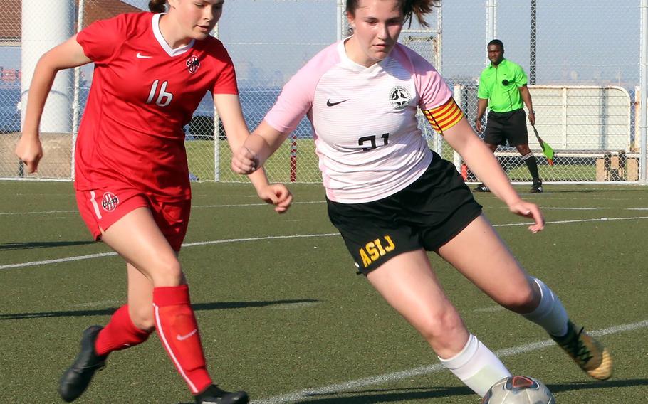 ASIJ's Ava Vander Louw plays the ball as Kinnick's Lindsey Boran defends during Thursday's semifinal in the Far East Division I girls soccer tournament. The Red Devils won 3-1 on penalties.