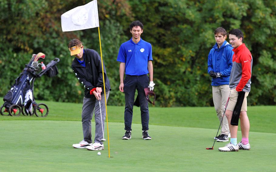 Ramstein's Matt Miller putts on the day's final hole at the DODEA-Europe high school golf championships in Wiesbaden, Germany, in October 2019, as teammate Chris Angeles, Stuttgart's Jonathan Keathley and Kaiserslautern's Mathias Perrin watch. Golfers will take to the links this season with coronavirus precautions.