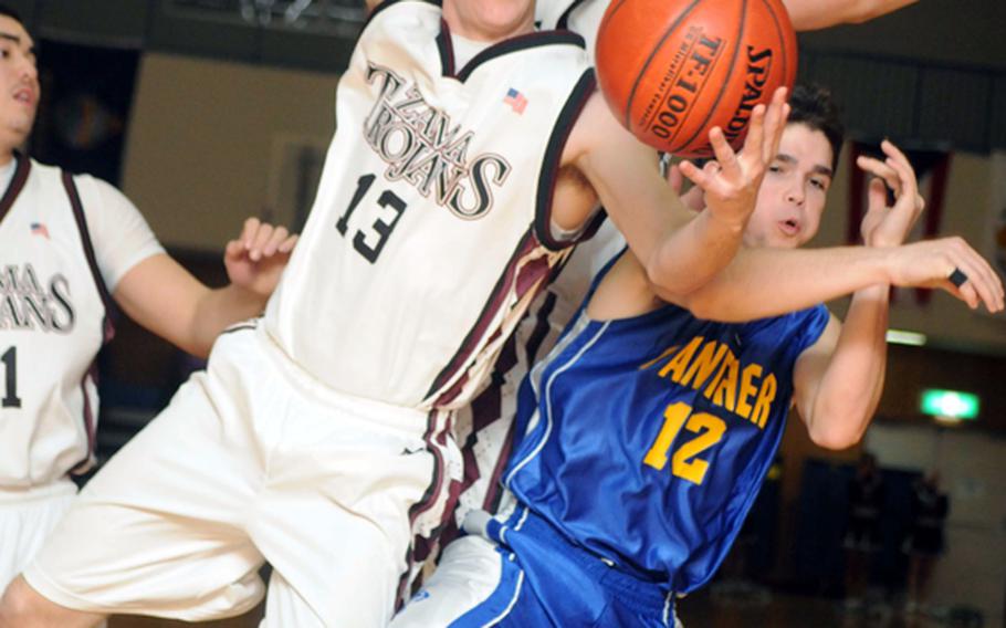 Zama American's Joey Bullington (13) battles Yokota's Kazdan Batey for a rebound during Tuesday's game at Camp Zama, Japan. The visiting Panthers beat the Trojans 73-53.