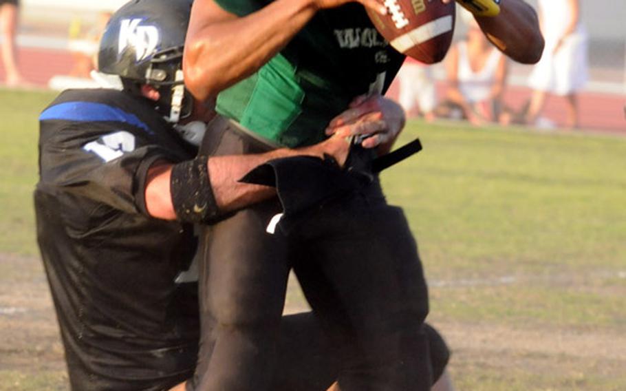 Joint Task Force Wolf Pack quarterback Jonathan Gibbs looks to pass while in the grasp of Kadena Dragons defender Nicholas Warden during Saturday's U.S. Forces Japan-American Football League South Division game at Kadena Air Base, Okinawa.