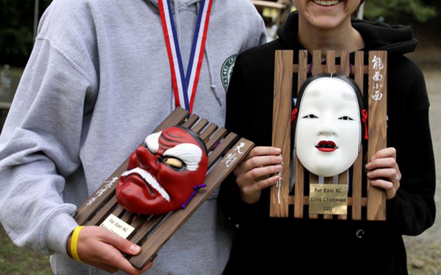 Kubasaki Dragons freshman Erik Armes, the Okinawa Activities Council island champion, and Amanda Henderson of Seoul American, the senior two-time Korean-American Interscholastic Activities Council champion, display their Far East Cross-Country Meet 3.1-mile individual race championship hardware after the 6.2-mile team-relay portion of the 2011 Far East High School Cross-Country Meet at Tama Hills Recreation Center, Tokyo on Nov. 8, 2011. They won their respective gold medals on Monday in the 3.1-mile individual race portion of the meet.