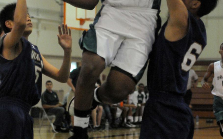 Kubasaki Dragons junior Jaysyn Brown threads his way to the basket between two Kitanakagusuku defenders during Saturday's season-opening game at  Kubasaki High School, Okinawa. The Dragons beat the Fighting Lions, 77-59.