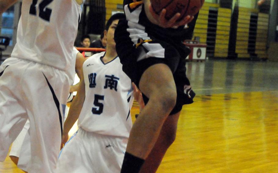 Kadena Panthers guard Jalen Amos drives to the basket ahead of Konan Shisa defenders Kenichiro Kinjo (12) and Muneyuki Machida (5) during the boys championship game in the 6th Okinawa-American Basketball Shootout on Jan. 22, 2012, at Camp Foster, Okinawa. Kadena edged Konan 73-67, ending a two-year losing streak to the Shisa in the Shootout championship.